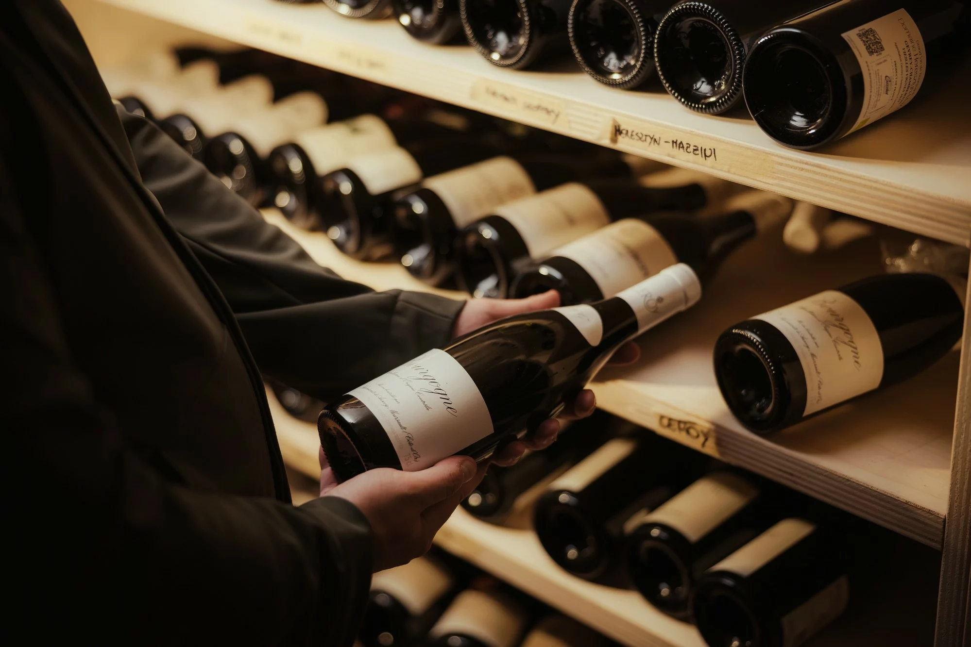 Primo piano su bottiglia di vino tra le mani del sommelier.